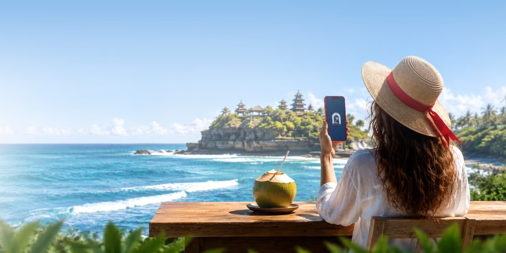 Two travelers smiling at a phone in front of a Balinese temple by the sea